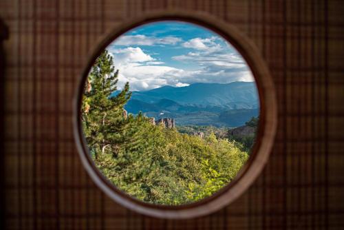 a view of a mountain through a round window at Хотел "Скалите", Skalite Hotel in Belogradchik