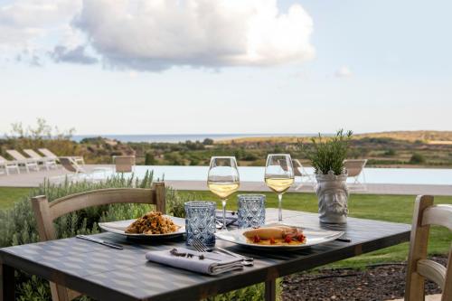 a table with two glasses of wine and food on it at I Carusi Relais in Noto