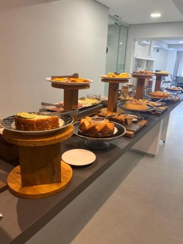 a buffet line with different types of cakes and pies at Express Floripa Residence in Florianópolis