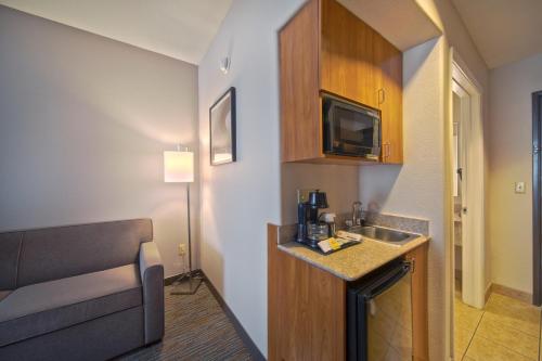 a small hotel room with a sink and a couch at Wingate by Wyndham Houston Bush Intercontinental Airport in Houston