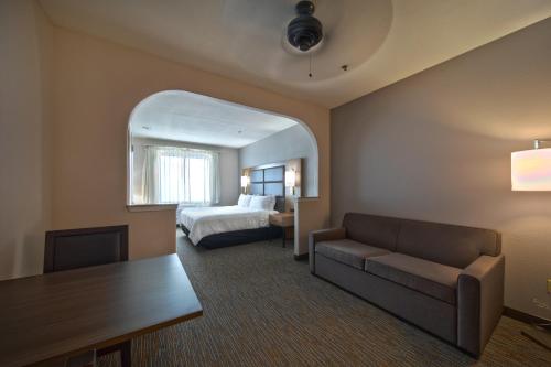 a hotel room with a bed and a couch and a table at Wingate by Wyndham Houston Bush Intercontinental Airport in Houston