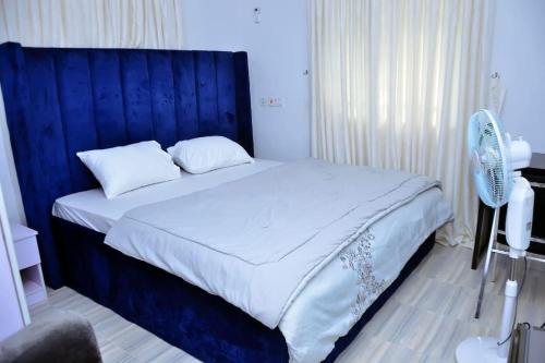 a bed with a blue headboard in a bedroom at Frankie’s Place: A spacious 4-bedroom home in Ondo