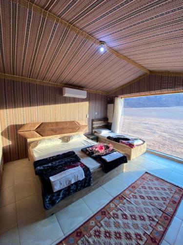 een slaapkamer met 2 bedden en een groot raam bij Mountain Magic Camp Wadi Rum in Wadi Rum