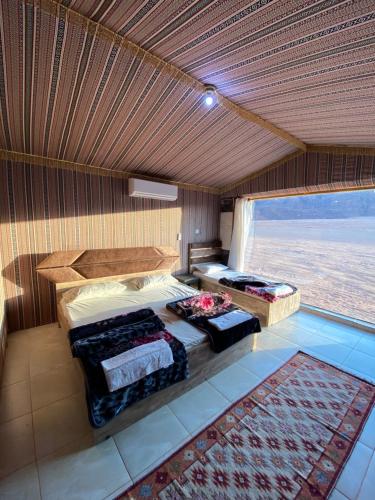 Un dormitorio con dos camas y una gran ventana. en Mountain Magic Camp Wadi Rum, en Wadi Rum