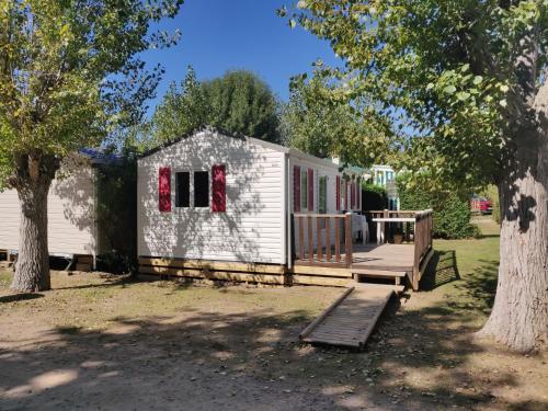 a small white house with a porch and a deck at Camping les Mancellieres in Avrillé