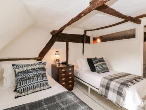 a bedroom with two beds and a night stand in a attic at 1 Peacock Cottage in Salisbury