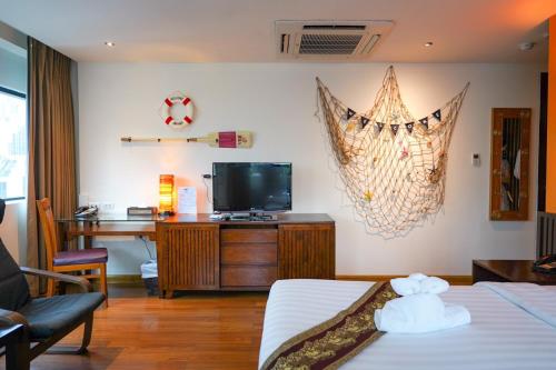 a room with a bed and a desk and a tv at Hotel Mermaid Bangkok in Bangkok
