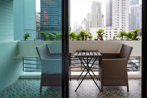a table and chairs on a balcony with a view of a city at Hotel Mermaid Bangkok in Bangkok