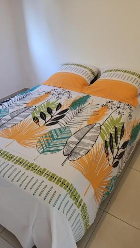a bed with a colorful comforter on top of it at Villa Creole alamanda 2 in Petite Île