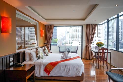 a bedroom with a bed and a desk and a large window at Hotel Mermaid Bangkok in Bangkok