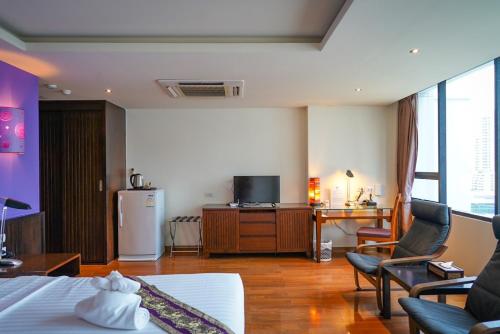 a hotel room with a bed and a desk and a television at Hotel Mermaid Bangkok in Bangkok