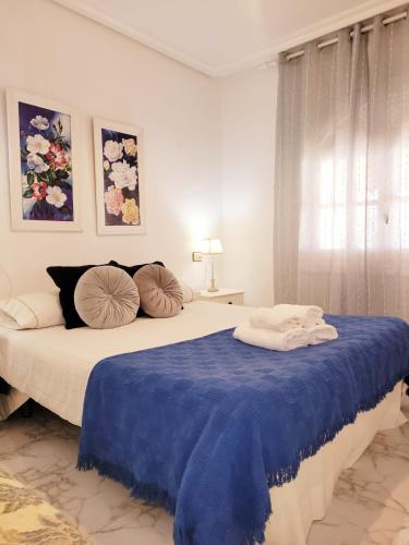 a white bedroom with a large bed with blue sheets and pillows at Casa Rural El Cornijal - Piscina Privada in San Javier