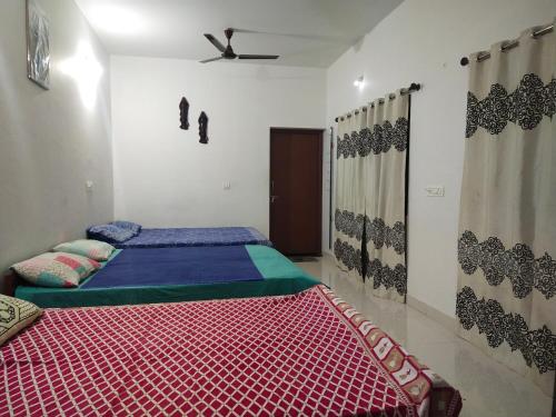 a bedroom with two beds and a ceiling fan at Haveli Holiday Home in Mudigere
