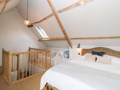 a bedroom with a white bed and a staircase at Rockstowes House in Dursley
