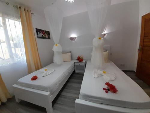 ein weißes Zimmer mit 2 Betten mit Blumen darauf in der Unterkunft Villa santa avec piscine et jardin in Pointe aux Piments