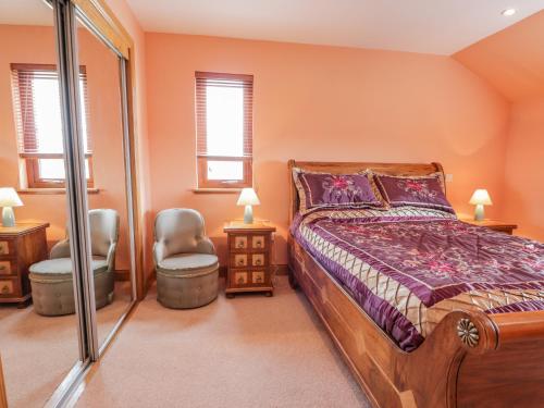 um quarto com uma cama e duas cadeiras e duas janelas em Lossiemouth Bay Cottage em Lossiemouth