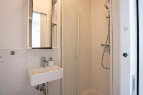 a white bathroom with a sink and a shower at Sundeck botel - party boat in Bratislava