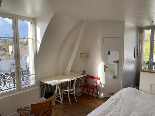 a bedroom with a bed and a desk and windows at Amazing view in Montmartre in Paris