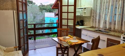 a kitchen with a table and a view of a balcony at Do Sonho a Realizacao in Monte Verde