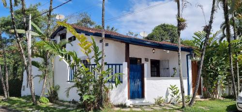 una pequeña casa blanca con una puerta azul en Casinha D&K - Itaguá, en Ubatuba