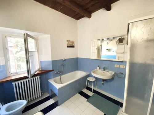 baño azul y blanco con bañera y lavamanos en Villa Ginevri, La casa vacanze immersa nel verde, en Mondavio