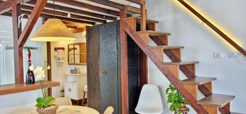 escalera de caracol de madera en una habitación con mesa y lámpara en Casinha D&K - Itaguá, en Ubatuba
