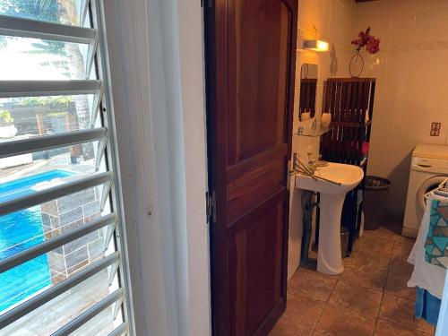 uma casa de banho com um lavatório, um espelho e uma porta em charmante maison em Sainte-Marie