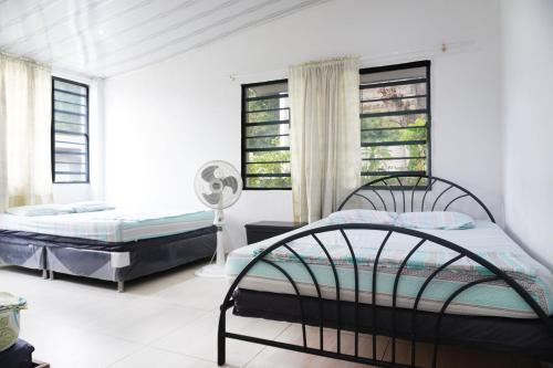 2 camas en una habitación blanca con ventanas en Casa Quinta Villa Carolita, en Melgar