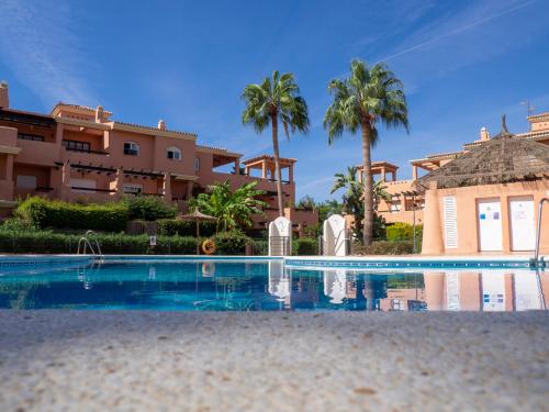a swimming pool in front of a house with palm trees at Bajo con jardín privado # Largas estancias # Playa 8min # Chill out in Vera