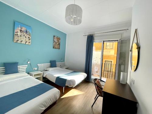 Habitación de hotel con 2 camas, escritorio y ventana en Pensión Bertolín en Barcelona