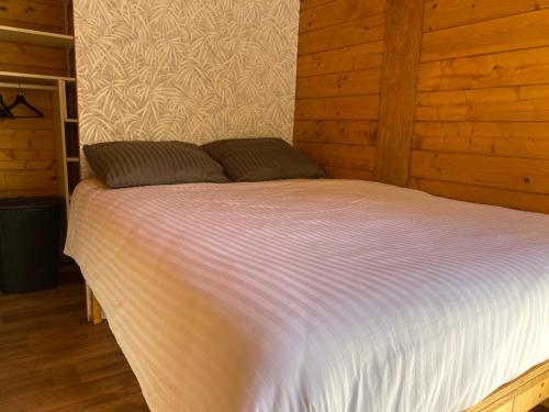 uma cama grande num quarto com paredes de madeira em Boshuisje em Enschede