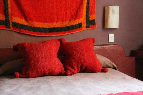 two red pillows sitting on top of a bed at Posada La Guadalupe in Tafí del Valle