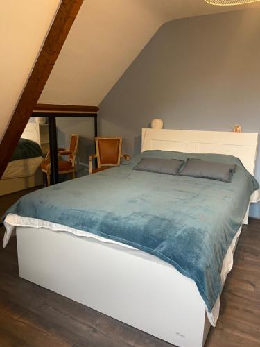 une chambre avec un grand lit avec une couette bleue dans l'établissement L’Atypique, à Villers-sur-Mer