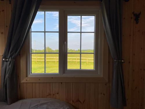 a bedroom with a window with a view of a field at Beautiful 1 Bed Shepherd Hut in Warwickshire in Warwick