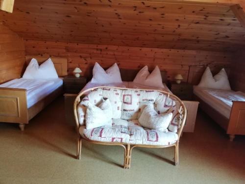 Pokój z 2 łóżkami i krzesłem z poduszkami w obiekcie Biobauernhof Klaushof w mieście Bischofshofen