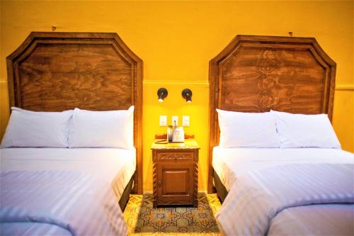a bedroom with two beds and a table with a phone at Hotel Real Toledo by Kavia in Mérida