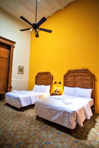 two beds in a bedroom with a yellow wall at Hotel Real Toledo by Kavia in Mérida