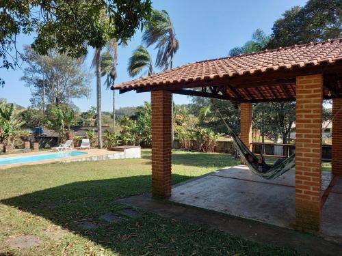 patio con amaca sotto un padiglione accanto alla piscina di Cabana na Serra do Itaqueri com fogão a lenha e churrasqueira a Itirapina