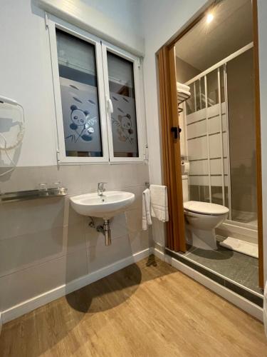 baño con lavabo y aseo y ventana en Pensión Bertolín, en Barcelona