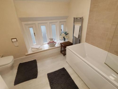 baño con bañera, aseo y ventana en The Cross Inn, en Hebden Bridge