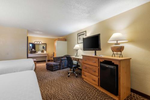 a hotel room with a bed and a desk with a television at Best Western Turquoise Inn & Suites in Cortez