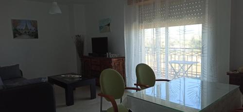 a living room with a glass table and a balcony at Piso Turístico Huétor Vega (Granada) in Huétor Vega