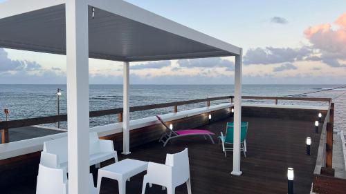 un balcón con sillas y mesas en un crucero en VILLA PHARE CARAÏBES Guadeloupe, en Le Moule