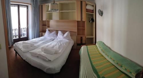 Schlafzimmer mit einem Bett mit weißer Bettwäsche und Kissen in der Unterkunft Appartamenti Callori Karin Codici Cipat 22039-AT-53550 AT-53551 in Canazei
