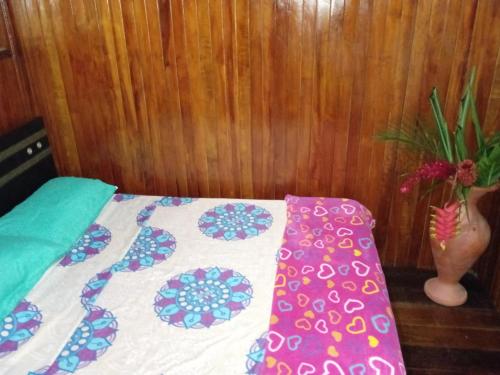 a bed with a quilt and a vase with a plant at casa en el parque tayrona in Santa Marta