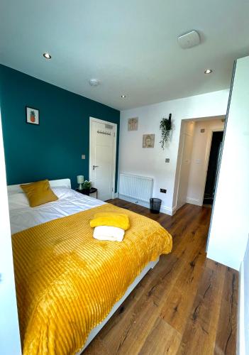 um quarto com uma cama grande e um cobertor amarelo em Beautiful Studio flat em Purley