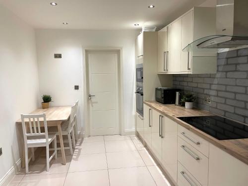 a kitchen with white cabinets and a table with a chair at Beautiful Studio flat in Purley