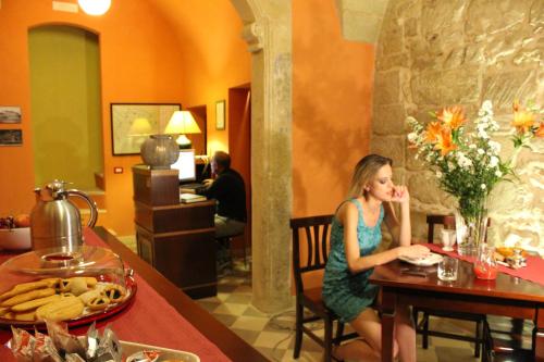a woman sitting at a table in a restaurant at B&B Residenza Pizziniaco in Lecce