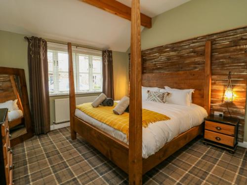 a bedroom with a bed with a wooden headboard at The Old Wagon Shed in Leven