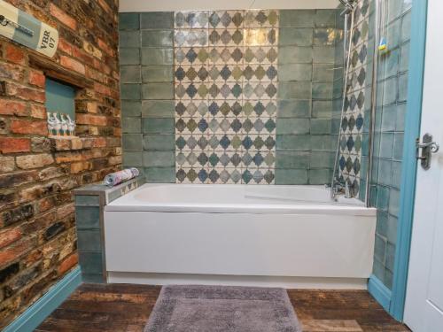 a bath tub in a bathroom with a brick wall at The Old Wagon Shed in Leven